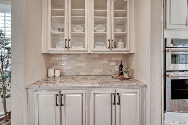 10761 Hillsboro Cir, Parker, CO 80134 - bar featuring backsplash, a textured wall, and stainless steel double oven