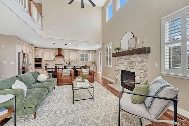 10761 Hillsboro Cir, Parker, CO 80134 - living area with light wood-type flooring, a towering ceiling, ceiling fan, and a stone fireplace
