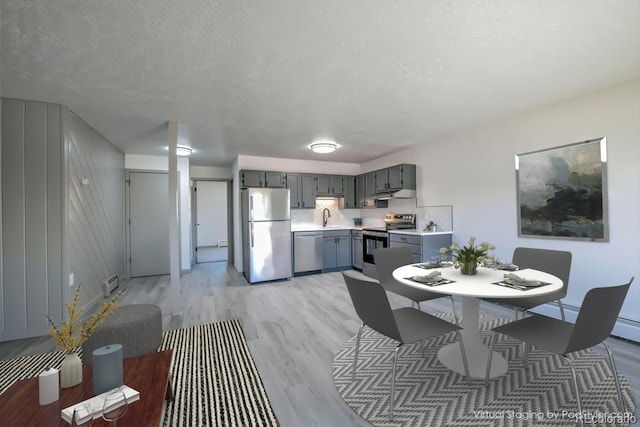 dining space featuring light hardwood / wood-style flooring, a baseboard radiator, a textured ceiling, and sink