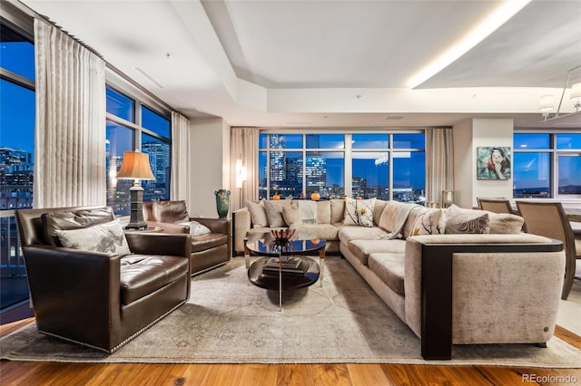 living room with a raised ceiling, hardwood / wood-style floors, and an inviting chandelier