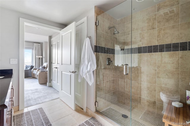 bathroom featuring toilet, a shower stall, and tile patterned floors