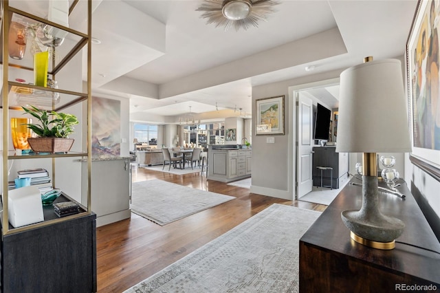 interior space featuring light wood-style floors, baseboards, and a raised ceiling