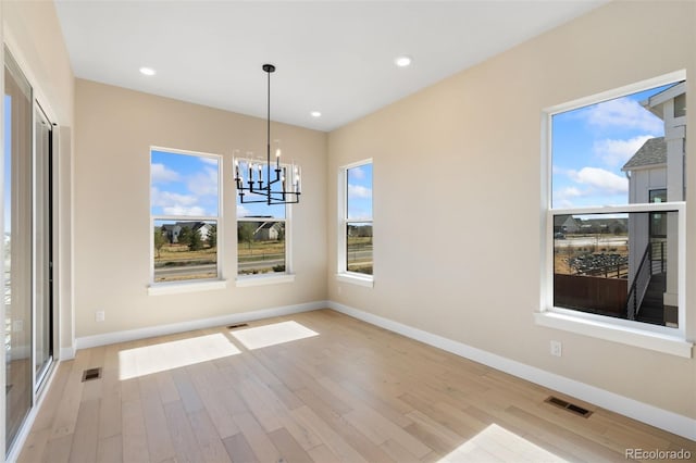 1585 Winter Glow Dr, Windsor, CO 80550 - unfurnished dining area with a chandelier, light wood-style floors, a healthy amount of sunlight, and baseboards