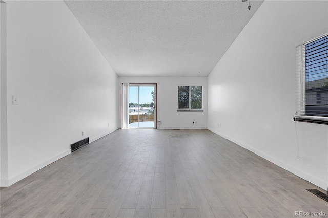 7610 S Garland St, Littleton, CO 80128 - empty room featuring a textured ceiling, wood finished floors, and lofted ceiling