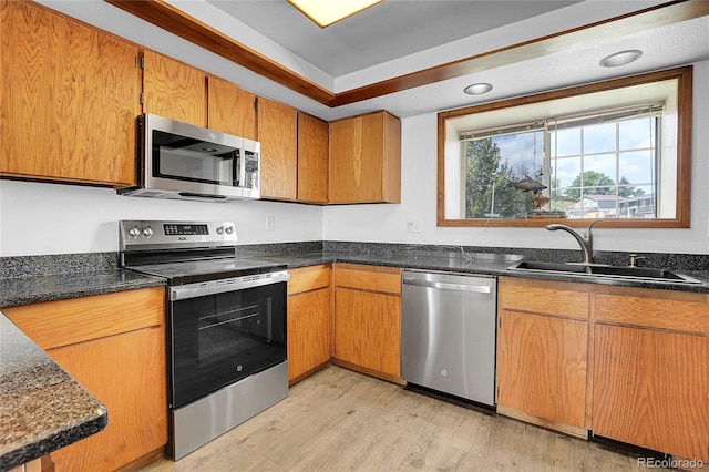 7610 S Garland St, Littleton, CO 80128 - kitchen with appliances with stainless steel finishes, light wood-type flooring, dark stone countertops, and brown cabinets
