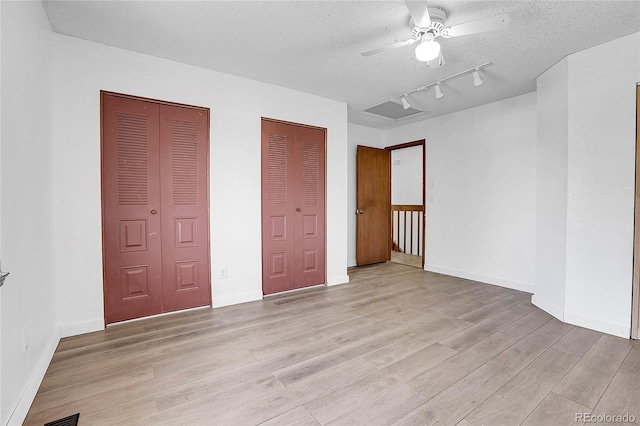 7610 S Garland St, Littleton, CO 80128 - unfurnished bedroom with light wood-style floors, multiple closets, a textured ceiling, ceiling fan, and rail lighting