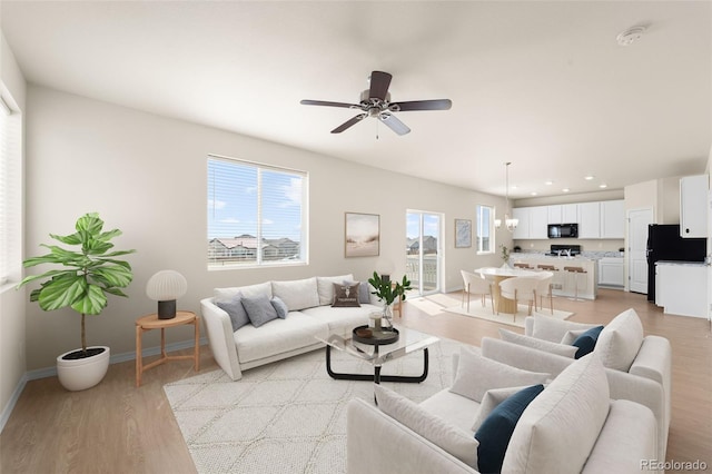 living room featuring baseboards, light wood-type flooring, recessed lighting, and a ceiling fan