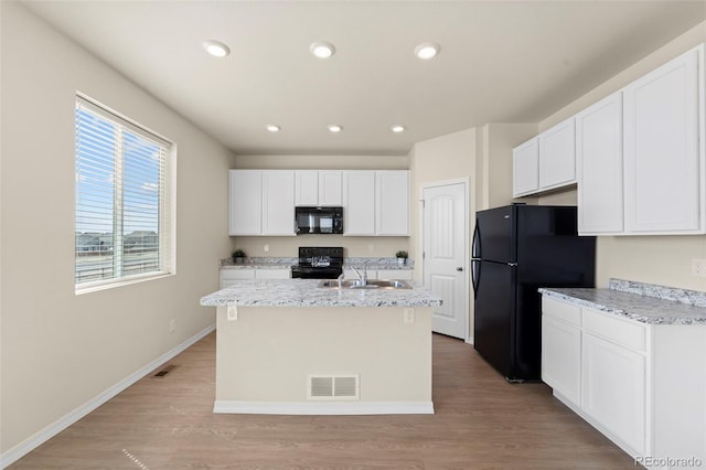 kitchen featuring visible vents, a sink, white cabinetry, and black appliances