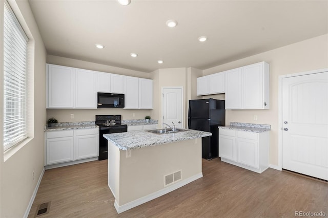 kitchen with light wood-type flooring, a sink, black appliances, and white cabinetry