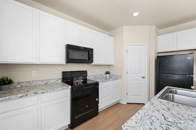 kitchen featuring light wood-style flooring, white cabinets, a sink, and black appliances