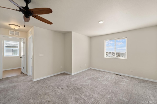 carpeted empty room with visible vents, a ceiling fan, and a healthy amount of sunlight