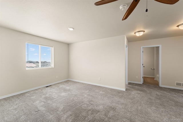carpeted empty room with visible vents, baseboards, and a ceiling fan