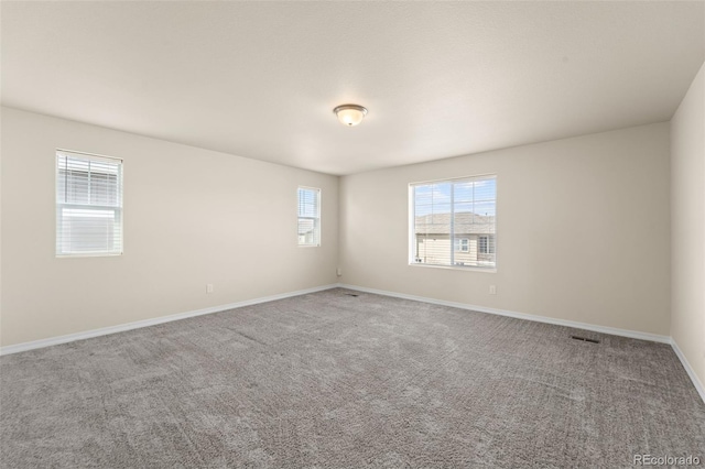 carpeted empty room with visible vents, baseboards, and a healthy amount of sunlight