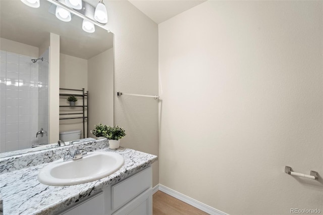 bathroom with baseboards, walk in shower, toilet, vanity, and wood finished floors