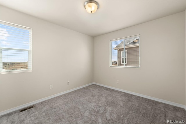 carpeted empty room featuring visible vents and baseboards