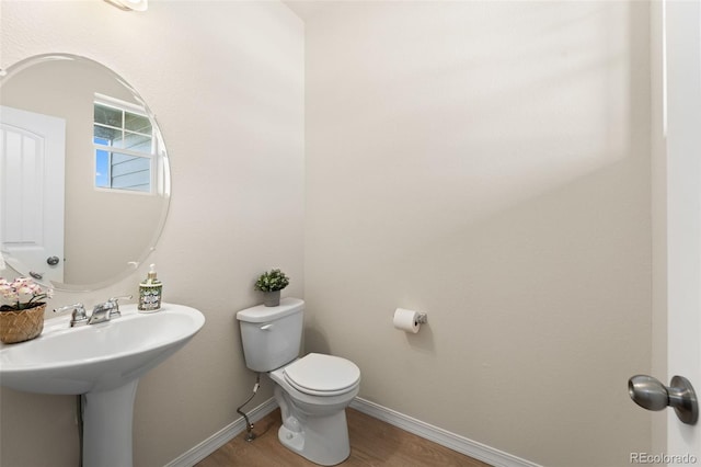 bathroom featuring baseboards, a sink, toilet, and wood finished floors