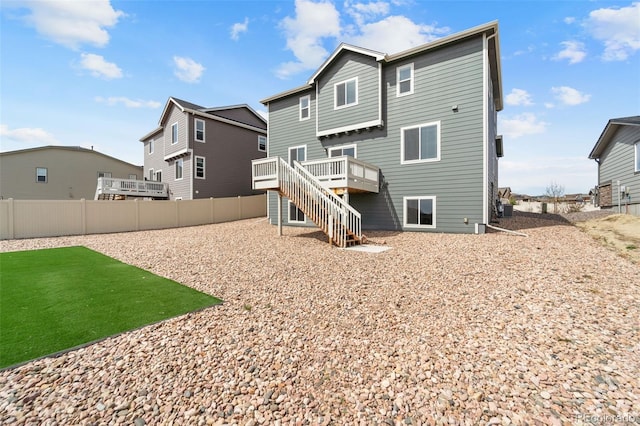 rear view of property featuring a yard, fence, a deck, and stairs