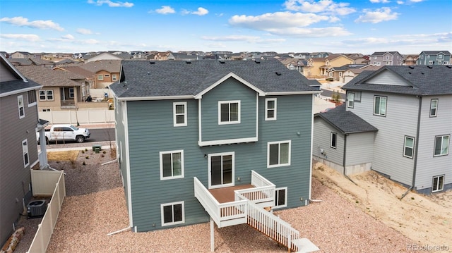 rear view of house with fence, a residential view, and roof with shingles