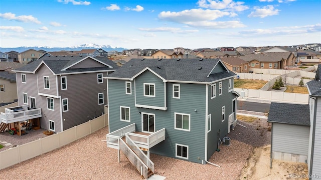 back of house with central AC, a fenced backyard, and a residential view