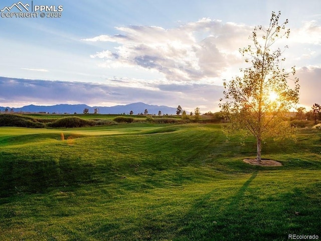 view of home's community with golf course view, a mountain view, and a lawn