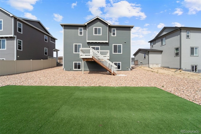 rear view of property featuring a yard, stairway, and fence