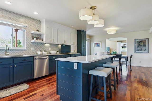 7289 Stroh Rd, Parker, CO 80134 - kitchen featuring stainless steel dishwasher, a sink, a breakfast bar, arched walkways, and dark wood-type flooring