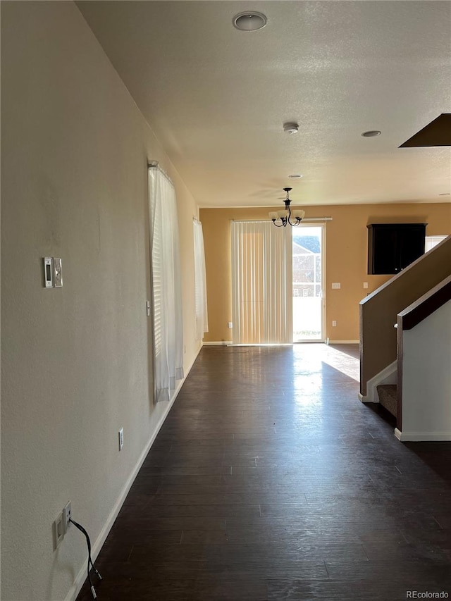 empty room with dark hardwood / wood-style flooring and an inviting chandelier