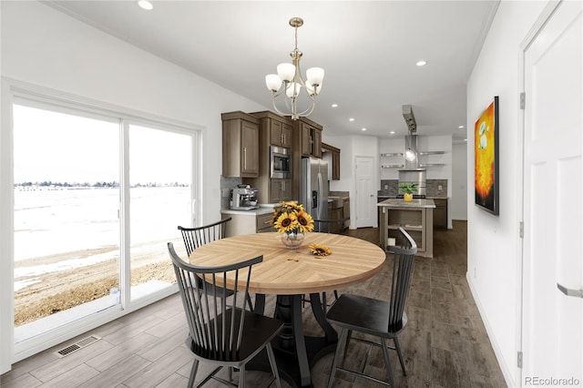 dining area featuring dark wood-type flooring, a water view, and a chandelier