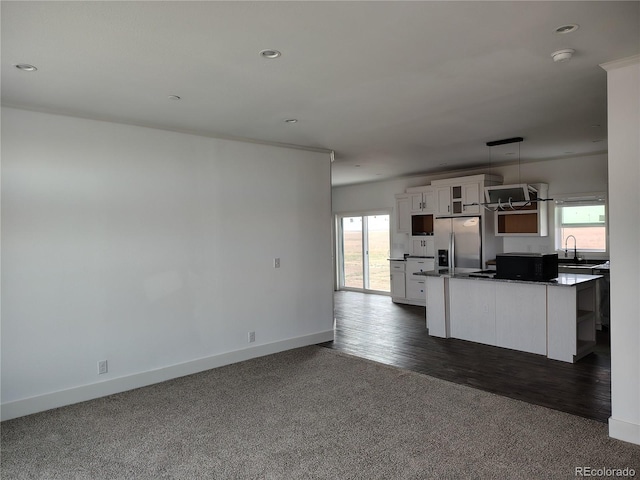 kitchen with a center island, pendant lighting, white cabinets, dark wood-type flooring, and stainless steel refrigerator with ice dispenser