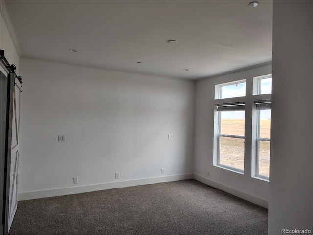 carpeted spare room featuring crown molding, a barn door, and plenty of natural light