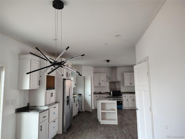 kitchen featuring wall chimney range hood, stainless steel fridge, white cabinetry, decorative light fixtures, and dark wood-type flooring