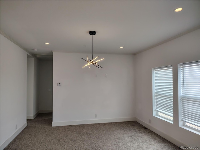 carpeted empty room featuring a notable chandelier and ornamental molding