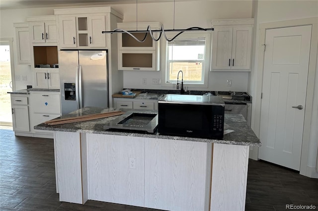 kitchen featuring a center island, stainless steel fridge, dark stone counters, pendant lighting, and white cabinets