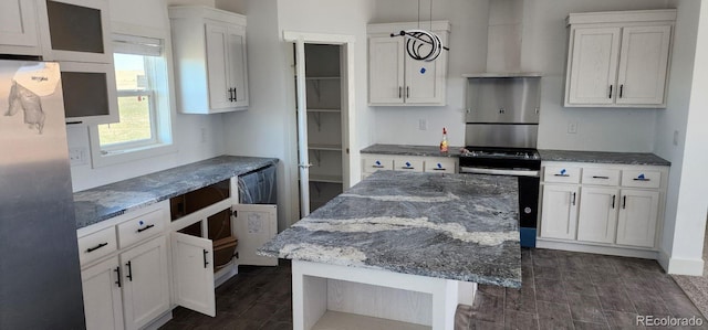 kitchen featuring dark hardwood / wood-style flooring, a kitchen island, white cabinets, and stainless steel refrigerator