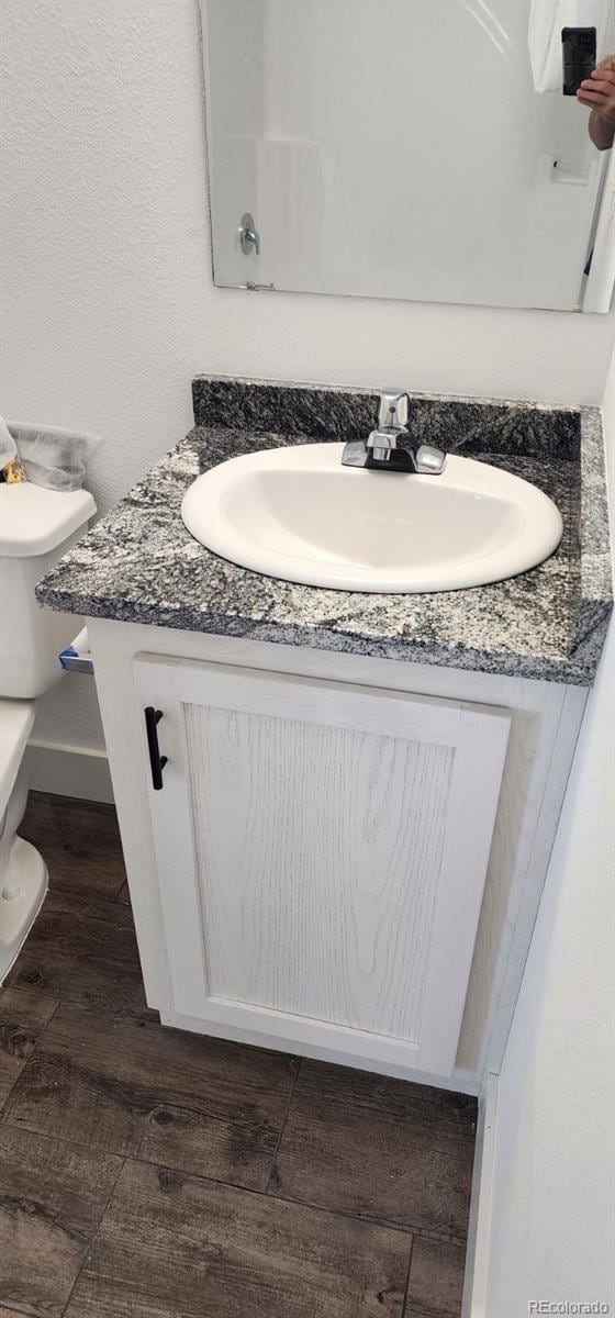 bathroom featuring vanity, hardwood / wood-style floors, and toilet