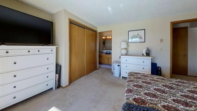 bedroom featuring light colored carpet, a textured ceiling, and ensuite bathroom