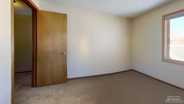 unfurnished room featuring light colored carpet and a textured ceiling