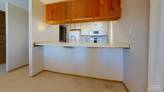 kitchen featuring white cabinetry, white appliances, kitchen peninsula, and light carpet