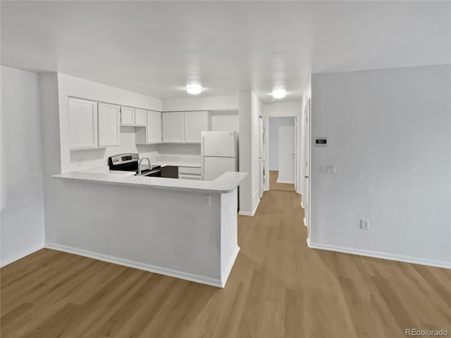 kitchen featuring white refrigerator, light wood-type flooring, white cabinetry, and kitchen peninsula