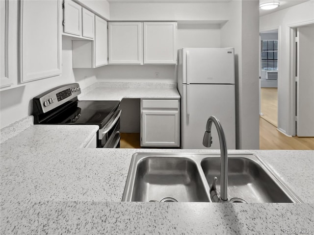 kitchen featuring stainless steel electric range, white refrigerator, white cabinetry, and sink