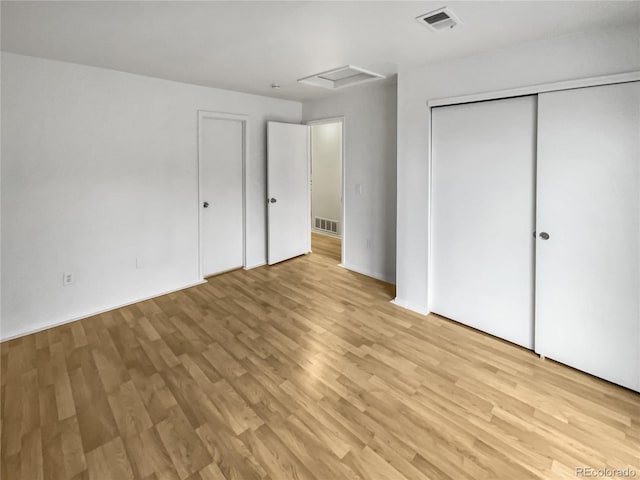 unfurnished bedroom with light wood-type flooring and a closet