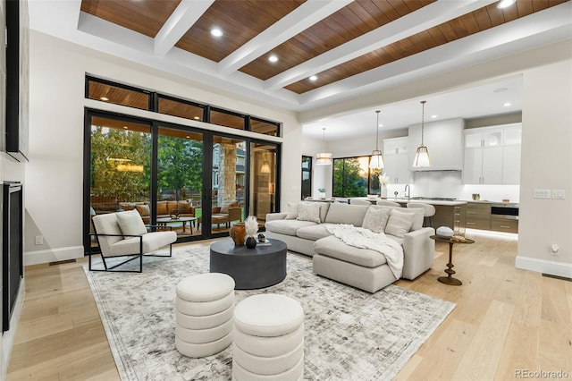 living room featuring a healthy amount of sunlight, beamed ceiling, wooden ceiling, and light wood-type flooring