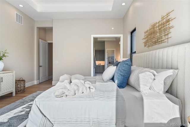 bedroom with a raised ceiling and wood-type flooring