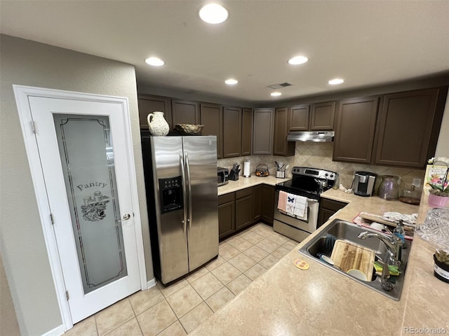 kitchen featuring tasteful backsplash, sink, light tile patterned floors, dark brown cabinetry, and stainless steel appliances