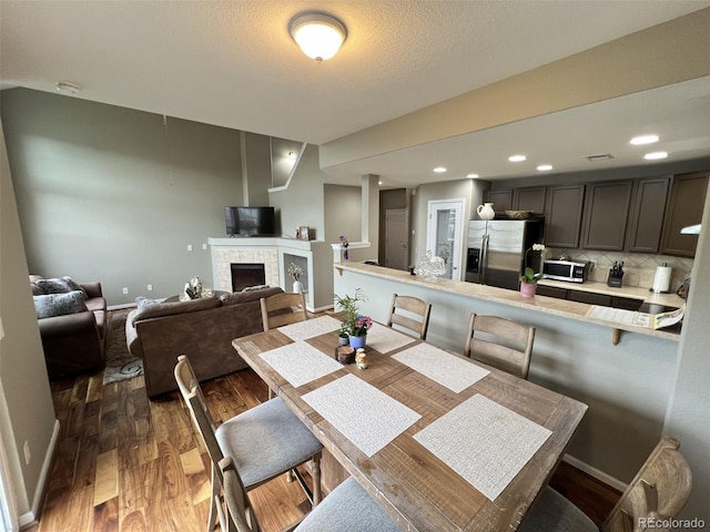 dining area featuring dark hardwood / wood-style floors, a textured ceiling, and a fireplace