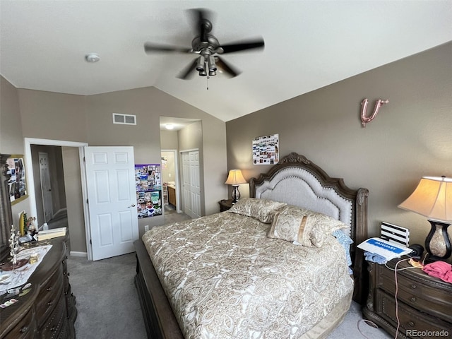 bedroom featuring lofted ceiling, ensuite bathroom, dark colored carpet, a closet, and ceiling fan