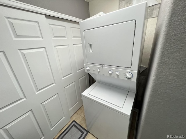 laundry room with stacked washing maching and dryer and light tile patterned flooring