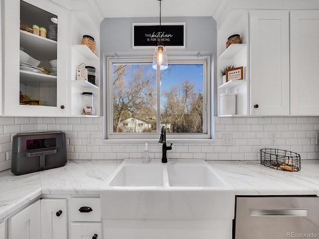 kitchen with decorative light fixtures, tasteful backsplash, white cabinetry, sink, and light stone countertops