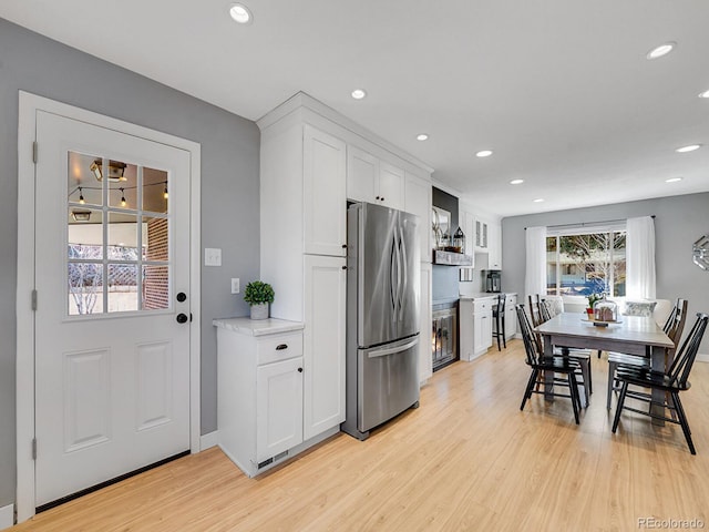 kitchen with white cabinetry, light wood-type flooring, and stainless steel refrigerator