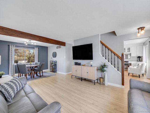 living room featuring a notable chandelier, beamed ceiling, and light wood-type flooring